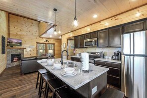 A modern kitchen with a central island, stainless steel appliances, and a fireplace.