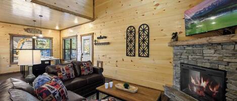 A cozy living room with a fireplace, wooden walls, and a television.