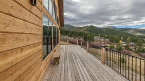 A wooden deck with a bench, overlooking a mountainous landscape.