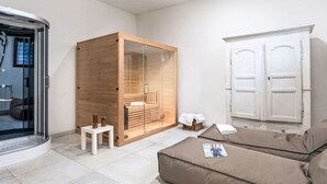 A modern, minimalist room with a glass-enclosed sauna, a wooden wardrobe, a white door, and a brown sofa. - Villa Isabella by Interhome (Vicchio)