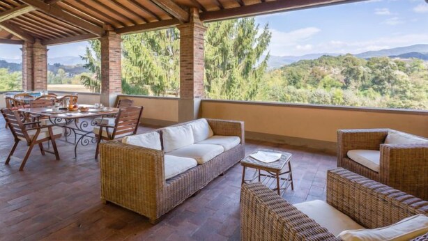 A covered patio with wicker furniture, a dining table, and chairs. - Villa Isabella by Interhome (Vicchio)