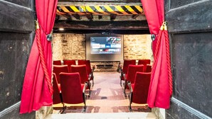 A cinema with red velvet curtains, a stone wall, and a screen displaying a Netflix interface. - Villa Isabella by Interhome (Vicchio)
