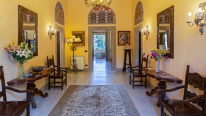 A hallway with ornate chandeliers, wooden chairs, and a patterned rug. - Villa Isabella by Interhome (Vicchio)