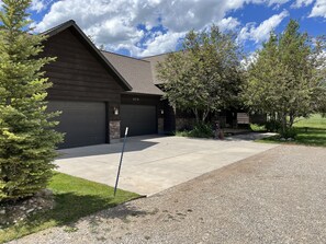 Une maison à deux étages avec un garage, une allée et une pelouse bien entretenue.