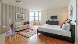 Une chambre à coucher moderne avec un lit, une télévision, un bureau et une fenêtre.