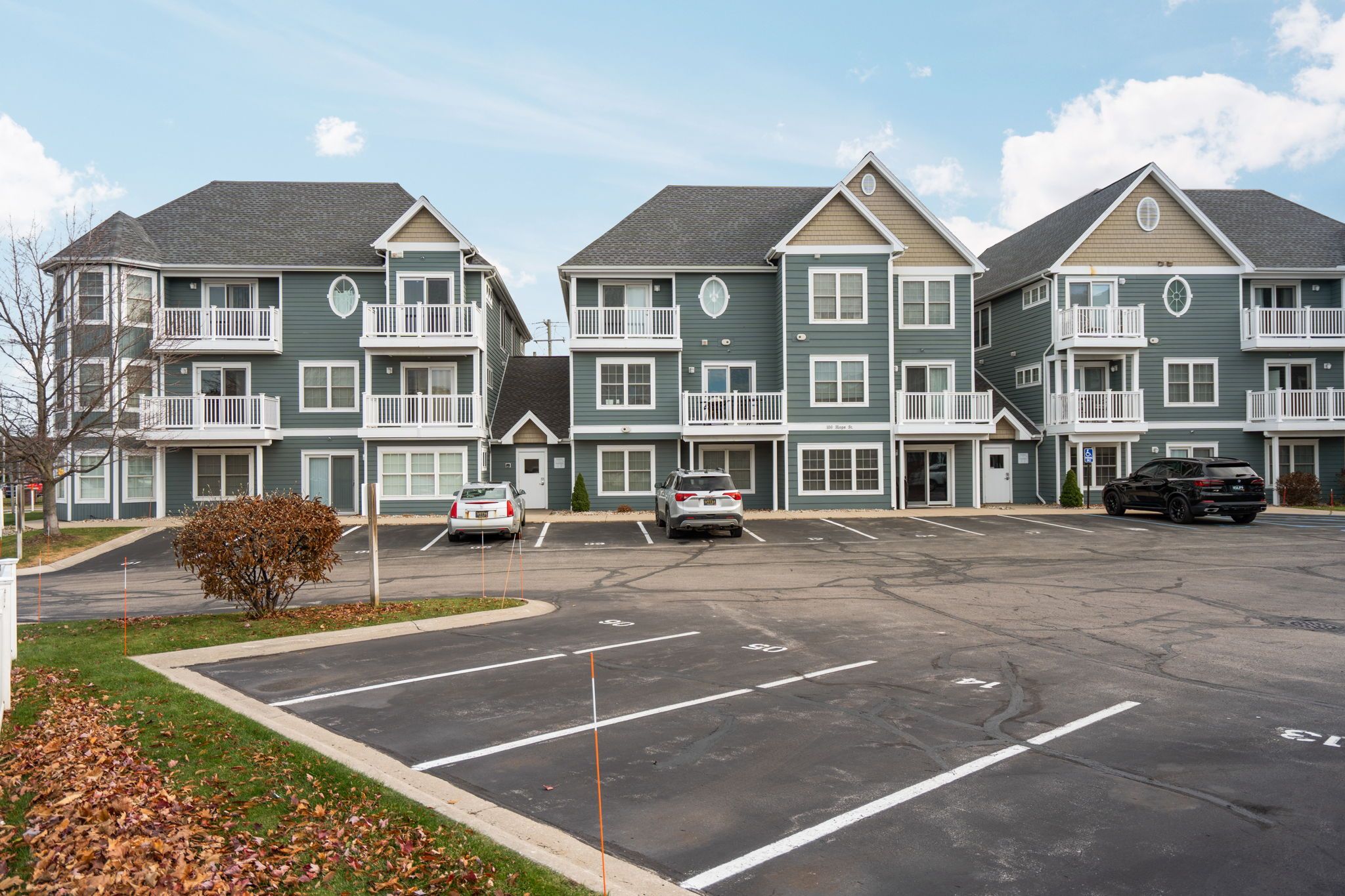 A multi-story residential building with a parking lot in front.