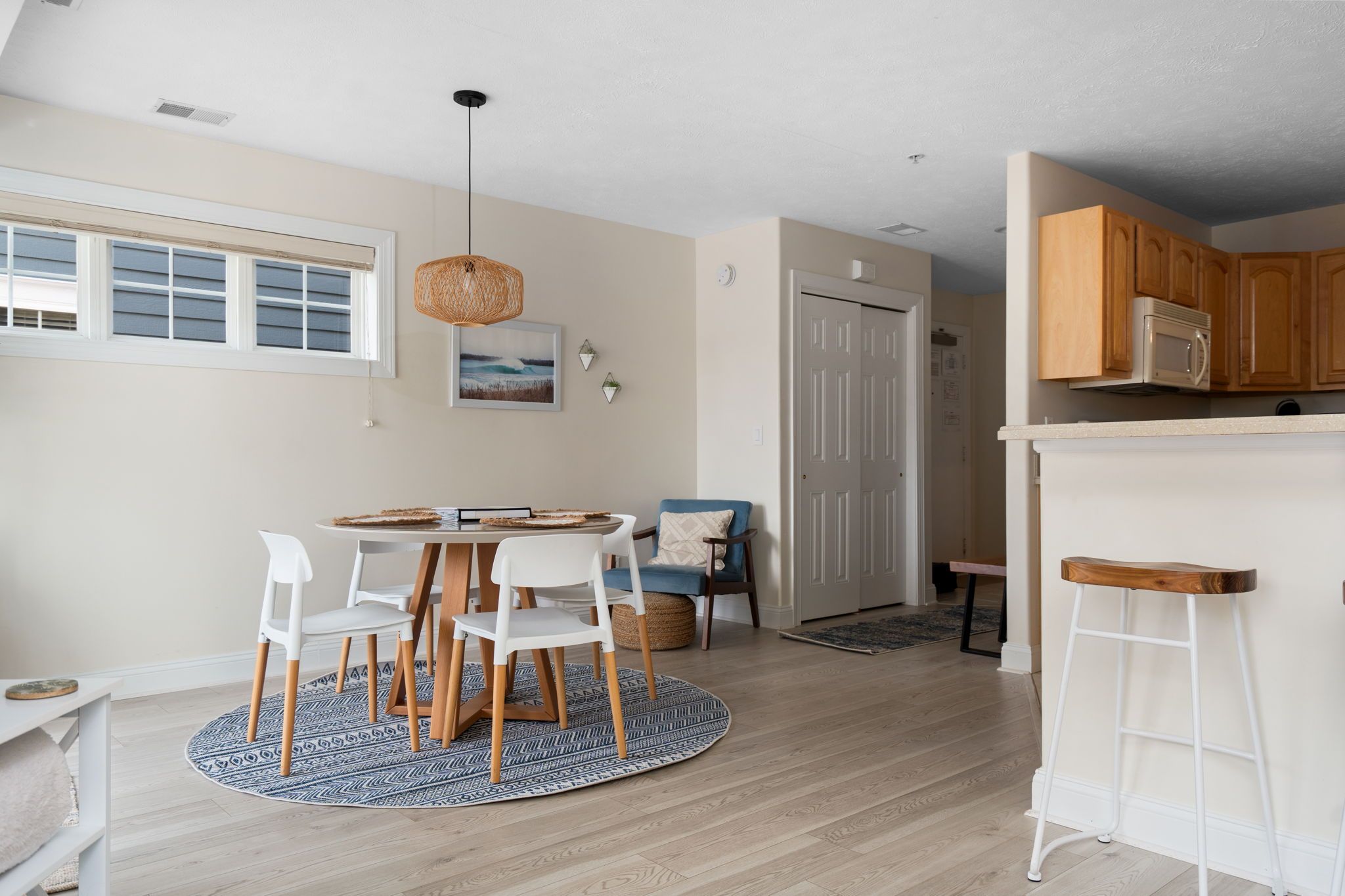 A modern kitchen with wooden cabinets, a white countertop, and a hanging light fixture.