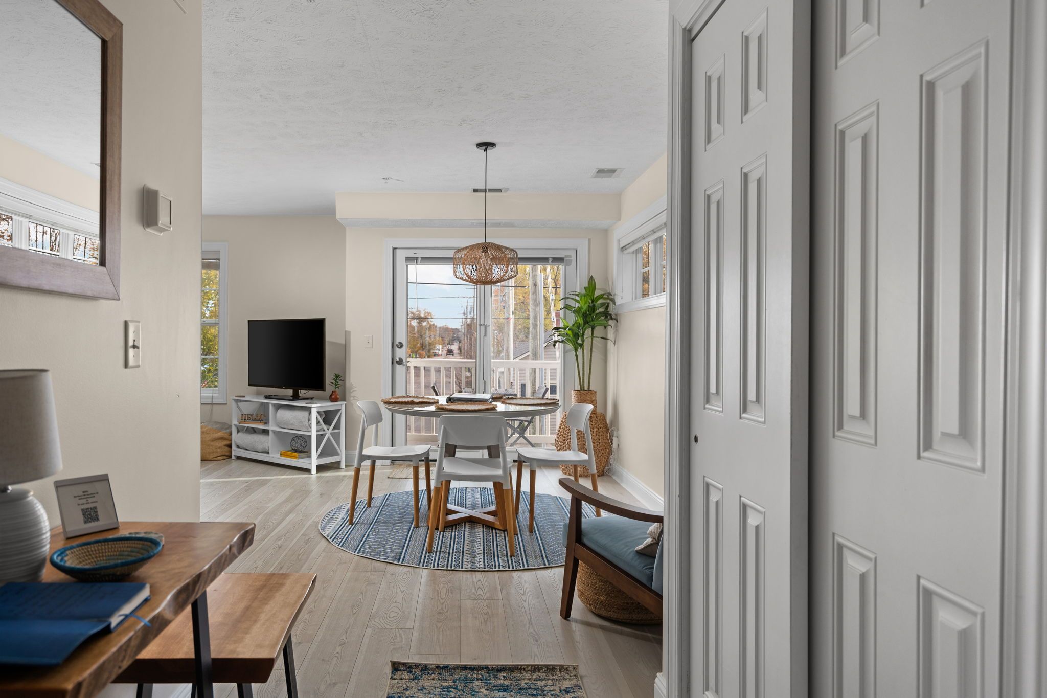 A modern living room with a television, seating area, and a dining space with a table and chairs.