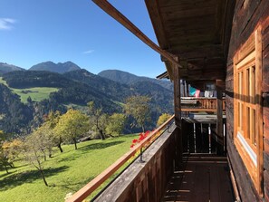 Un balcón de madera con vistas a un valle verde y montañas.