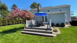 A house with a covered porch, a dining table with chairs, and a blue umbrella. - Historic Shoreline Home minutes to Stonington Village and Mystic! (Stonington)