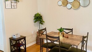 A dining area with a wooden table and chairs, a small side table with a plant, and a wall-mounted mirror arrangement. - Spacious 2bd apt in South Huntsville, close to Redstone Arsenal & downtown!! (Huntsville)