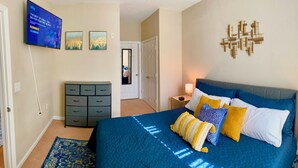 A bedroom with a large bed, a dresser, a TV, and a wall art piece. - Spacious 2bd apt in South Huntsville, close to Redstone Arsenal & downtown!! (Huntsville)