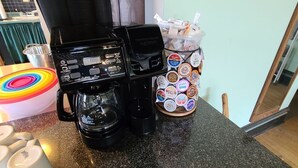 Une machine à café, un panier rempli de pots de yaourt et un bol coloré sur un plan de travail de cuisine.