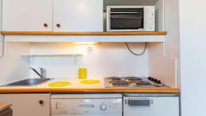 A compact kitchen with a built-in dishwasher, a stove, and a toaster oven. - Nécou 505 by Interhome (Les Menuires)