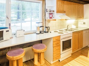 A kitchen with a stove, oven, sink, and two stools.