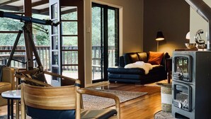 Een moderne woonkamer met een houten stoel, een zwarte bank en een houtkachel.