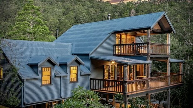 Een huis met twee verdiepingen, een balkon en een groot raam.