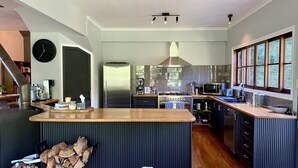Een moderne keuken met een centraal eiland, roestvrijstalen apparatuur en een groot raam dat voor natuurlijk licht zorgt.