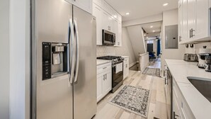 Une cuisine moderne dotée d’appareils électroménagers en acier inoxydable, de meubles blancs et d’un îlot central.