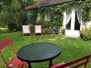 Un jardín con una mesa y sillas, una casa cubierta de hiedra y una puerta.