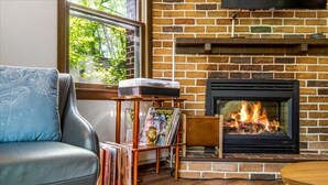 Een gezellige woonkamer met een schouw van baksteen, een leren bank en een klein tafeltje met vinylplaten.