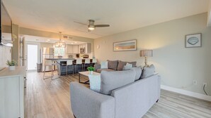 En moderne stue med en grå sofa, et spiseområde med bar og et køkken med rustfrie stålgadgetter.