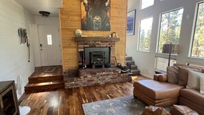 Un salón amplio con chimenea, piso de madera y un ventanal que proporciona luz natural.