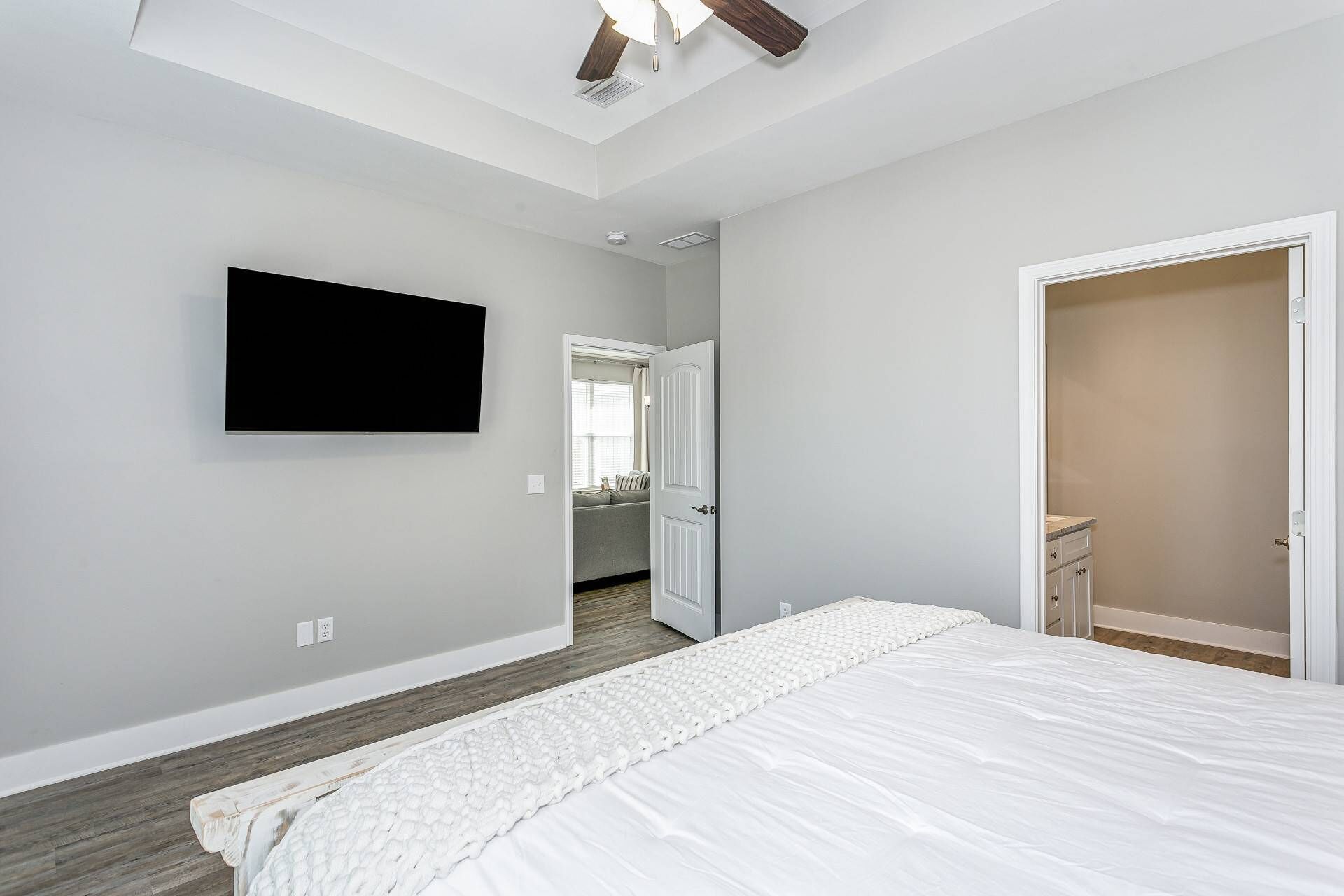 A bedroom with a bed, a TV mounted on the wall, a door, and a closet.