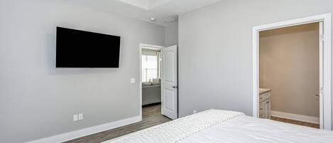 A bedroom with a bed, a TV mounted on the wall, a door, and a closet.
