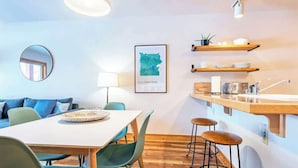 A modern kitchen with a wooden countertop, bar stools, and a hanging plant.