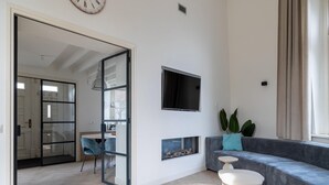 Ein modernes Wohnzimmer mit einer Couch, einem an der Wand montierten Fernseher und einem Kamin.