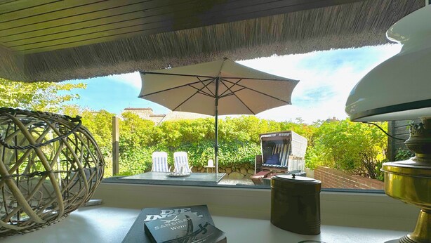 A room with a view of a garden, a wicker chair, a table with books, a lamp, and a globe. - PiPPA - PIPPA, Germany (List)