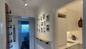A hallway with a wooden floor, a wall-mounted shelf, and a series of framed pictures. - PiPPA - PIPPA, Germany (List)