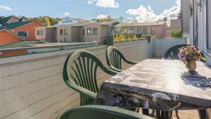 Een balkon met een eettafel, stoelen en een bloevas.