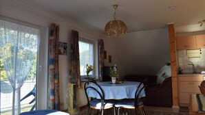 A dining area with a table set for four, a chandelier, and a view of the outside. - Apartment Pier 4 - Holiday apartments Hagen (Zinnowitz)