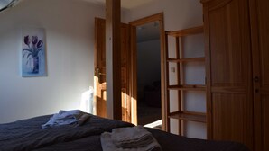 A bedroom with a bed, a wooden wardrobe, a mirror, and a painting of tulips on the wall. - Apartment Pier 4 - Holiday apartments Hagen (Zinnowitz)