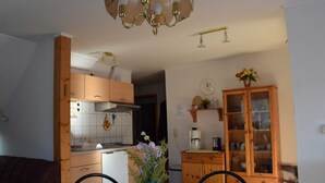 A dining area with a table, chairs, a vase of flowers, and a kitchen in the background. - Apartment Pier 4 - Holiday apartments Hagen (Zinnowitz)