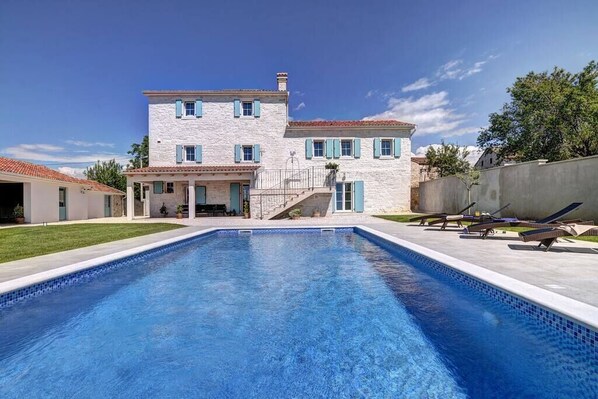 A two-story house with a swimming pool in the foreground.