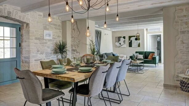 Comedor con una mesa de madera dispuesta para seis personas, rodeado de sillas tapizadas en gris.