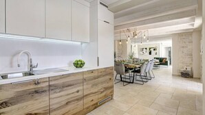 Una cocina moderna con armarios blancos, encimera de madera y un comedor con mesa y sillas.