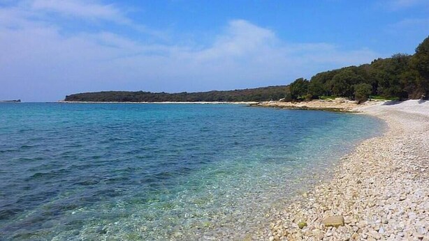 En vacker strand med småsten och ett lugnt hav.