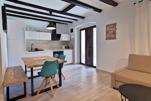 A modern kitchen with white cabinets, a wooden dining table, and teal chairs.