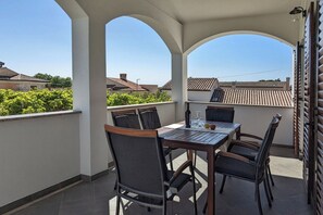 Une terrasse extérieure couverte, avec une table et des chaises, une bouteille de vin et un verre.