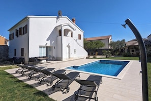 Une villa blanche dotée d’une piscine, de mobilier d’extérieur et d’un jardin.