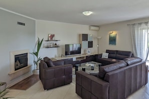 Un salon moderne avec un canapé d’angle, un téléviseur à écran plat et une cheminée.