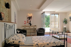 Une chambre à coucher avec un lit, un bureau, une chaise, une fenêtre et une plante.