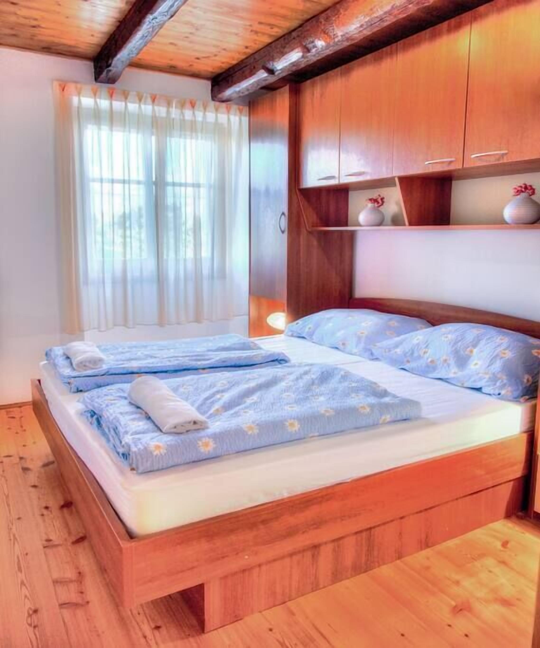 A wooden bed with two pillows and a blue floral bedspread.