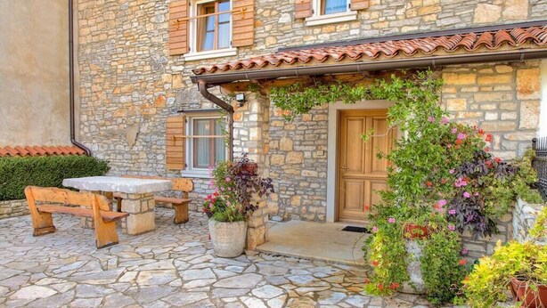 A stone building with a wooden door, a stone bench, and potted plants. - Istrian stone house with pool for 8 persons (Gajana)