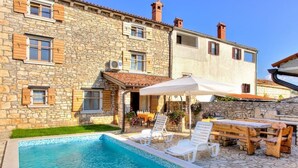 A stone building with a swimming pool, outdoor seating, and a covered patio area. - Istrian stone house with pool for 8 persons (Gajana)