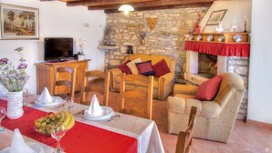 A cozy living room with a stone wall, wooden furniture, a fireplace, and a television. - Istrian stone house with pool for 8 persons (Gajana)